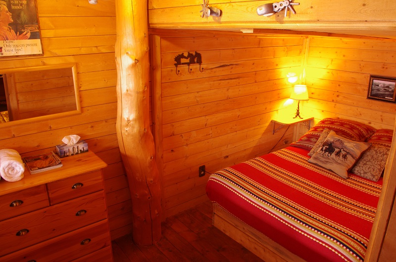 Bunkhouse queen bedroom lined with Cypress Hills lumber and upright log at Historic Reesor Ranch.